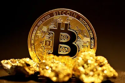 a bitcoin sitting on top of a pile of gold nuggets