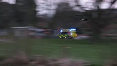 a police car driving down a street next to a lush green field